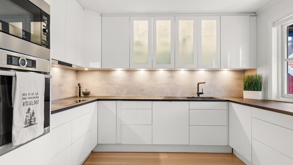 Sleek white kitchen with modern cabinets, wood countertops, and ambient lighting.